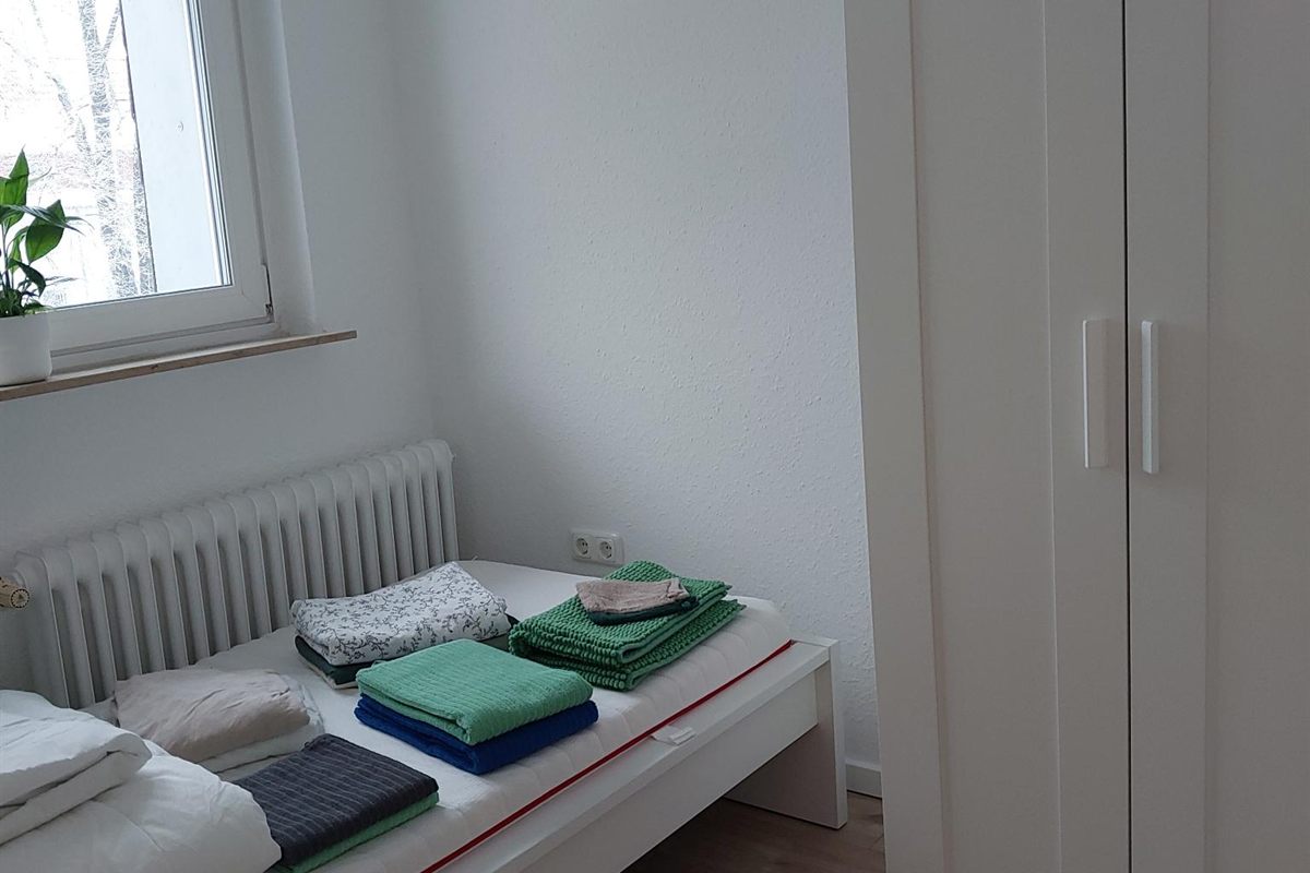 Schlafzimmer in einer Betreutes-Wohnen-Wohnung: Bett mit Bettwäsche, daneben ein Fenster